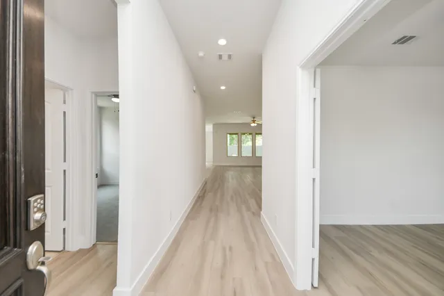 a view of a hallway with wooden floor and a bathroom