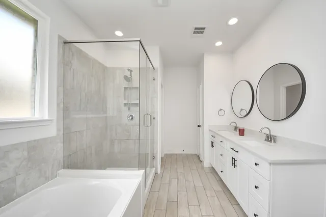 a bathroom with a tub sink double vanity and mirror