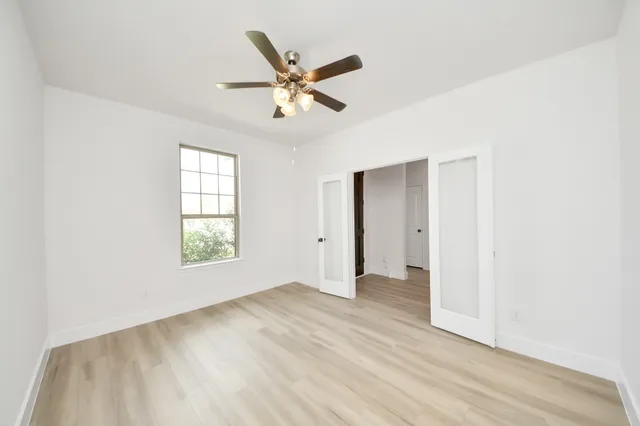 a view of an empty room with wooden floor and a window