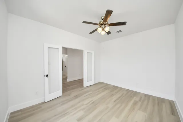 an empty room with wooden floor closet and ceiling fan
