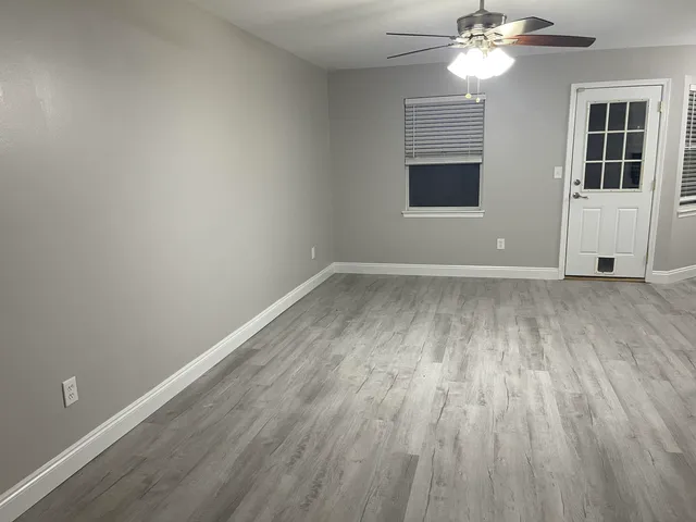 an empty room with wooden floor and windows