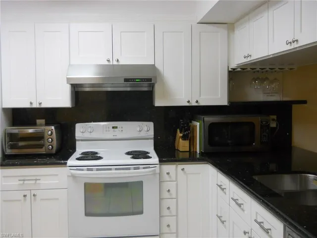 a kitchen with granite countertop white cabinets and black appliances