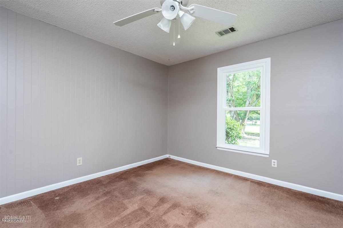 243 Lake Joy Road Perry, GA 31069 - Photo 15 of 29 an empty room with a chandelier fan and windows