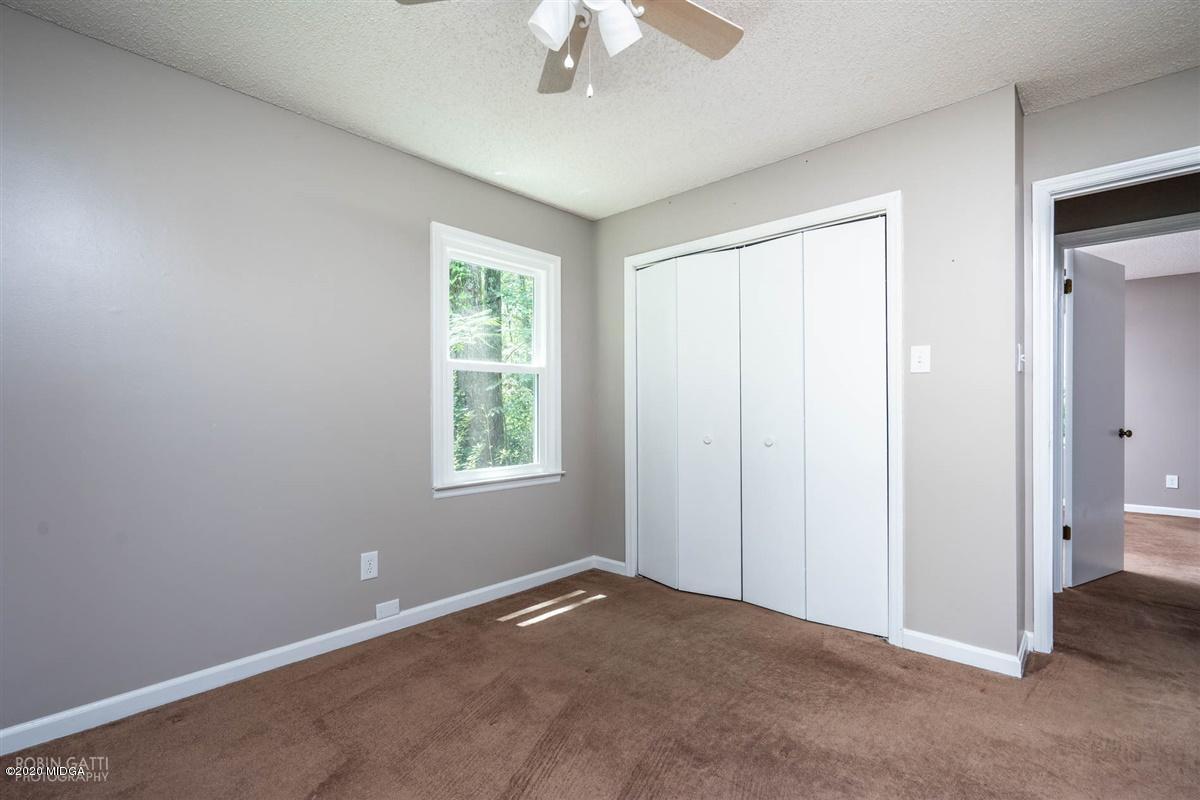 243 Lake Joy Road Perry, GA 31069 - Photo 19 of 29 an empty room with a chandelier fan and windows