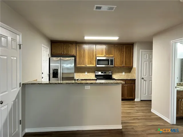 a kitchen with stainless steel appliances a microwave a sink and cabinets