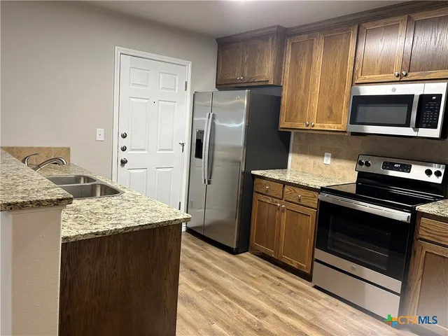 a kitchen with stainless steel appliances granite countertop a refrigerator stove and sink