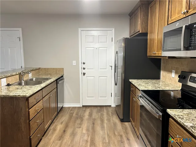 a kitchen with granite countertop a sink stove and refrigerator
