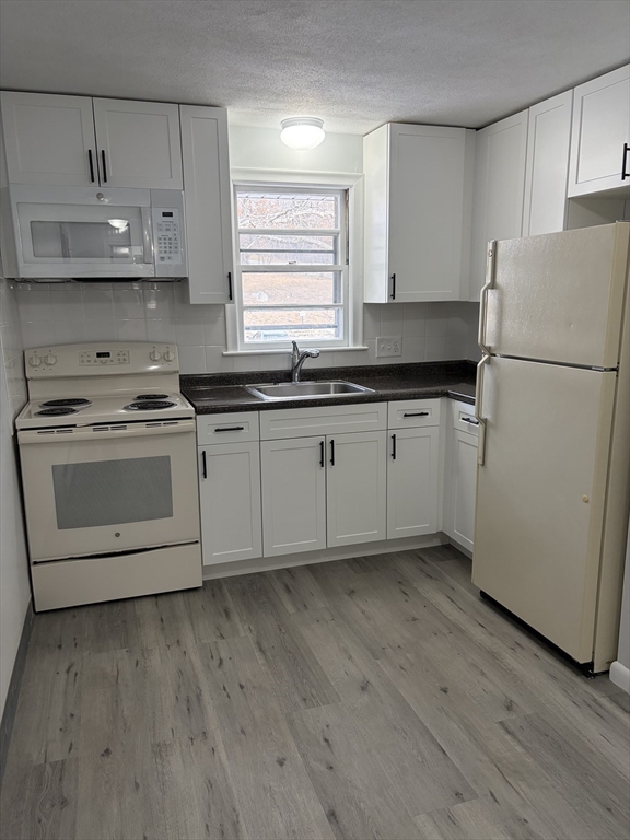 85 Trapelo Road, Unit 40 Waltham, MA 02452 - Photo 1 of 15 a kitchen with granite countertop white cabinets and white appliances