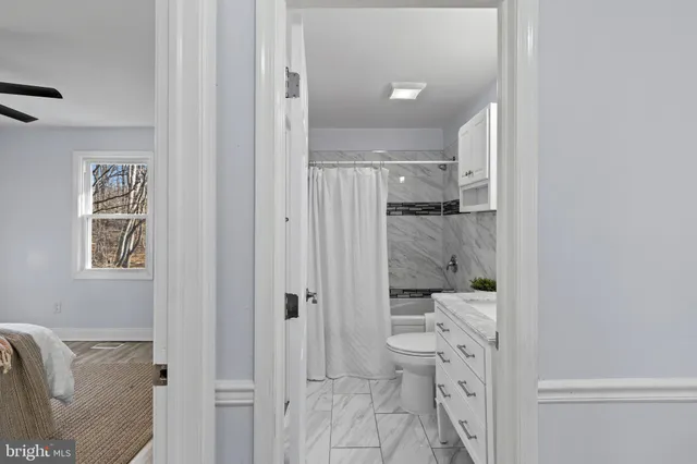 a bathroom with a granite countertop sink a toilet and shower