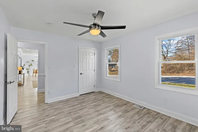 a view of empty room with wooden floor and fan