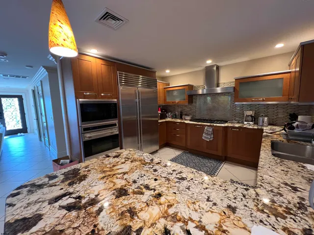 a kitchen with stainless steel appliances kitchen island granite countertop a sink stove and refrigerator