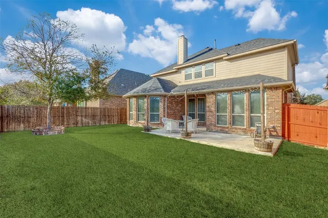 a backyard of a house with table and chairs and wooden fence