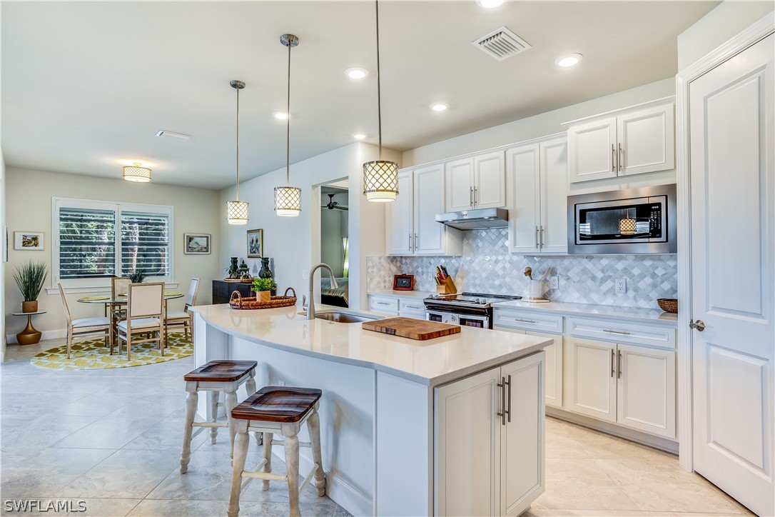 16495 Windsor Way Alva, FL 33920 - Photo 6 of 19 a kitchen with a sink a stove a refrigerator and white cabinets with wooden floor
