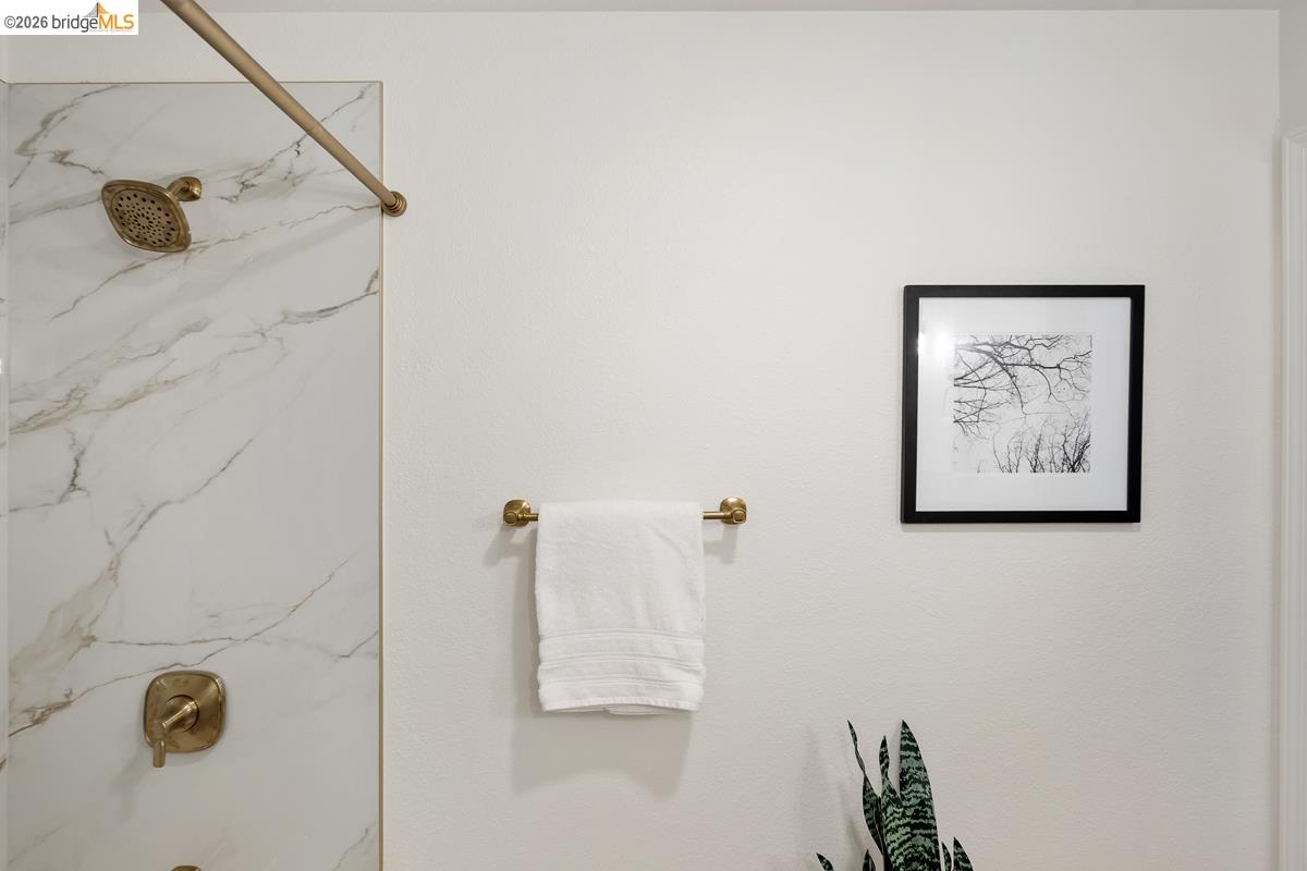 2029 Channing Way, Unit 3D Berkeley, CA 94704 - Photo 39 of 54 Shower with large-format marble-look wall tiling, featuring a gold-toned showerhead and control hardware