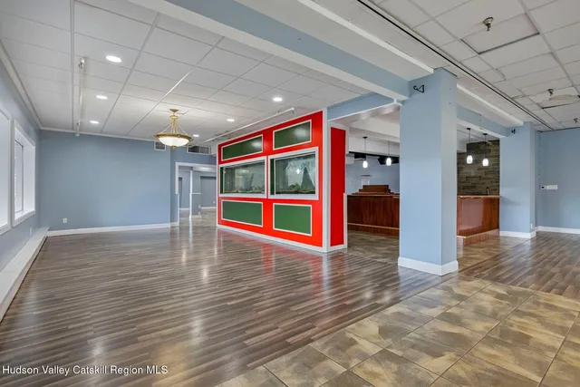 a view of a room with kitchen island stainless steel appliances wooden floor and chandelier