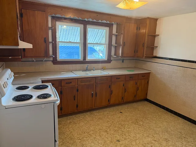 a kitchen with a sink a stove cabinets and a window
