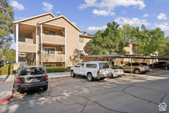 View of property featuring covered and uncovered parking