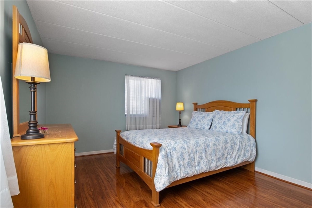40 High Street, Unit 207 Dedham, MA 02026 - Photo 28 of 41 a bedroom with a bed and a lamp on table