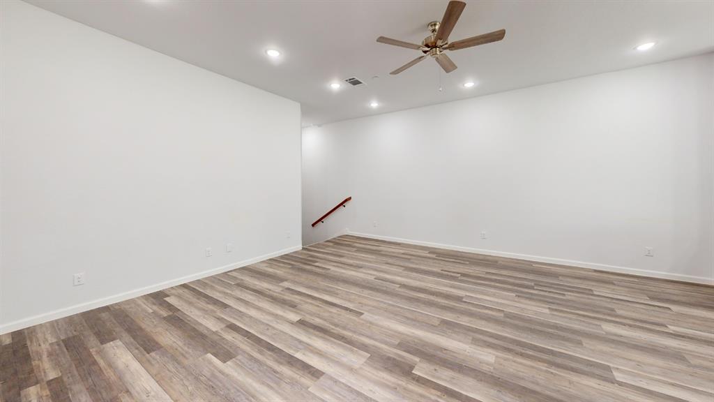 336 Buck Ridge Drive Frisco, TX 75068 - Photo 5 of 23 Spacious room featuring wood-finish flooring, recessed ceiling lighting, a ceiling fan with brushed bronze accents, white baseboards, and a visible staircase with a wood handrail