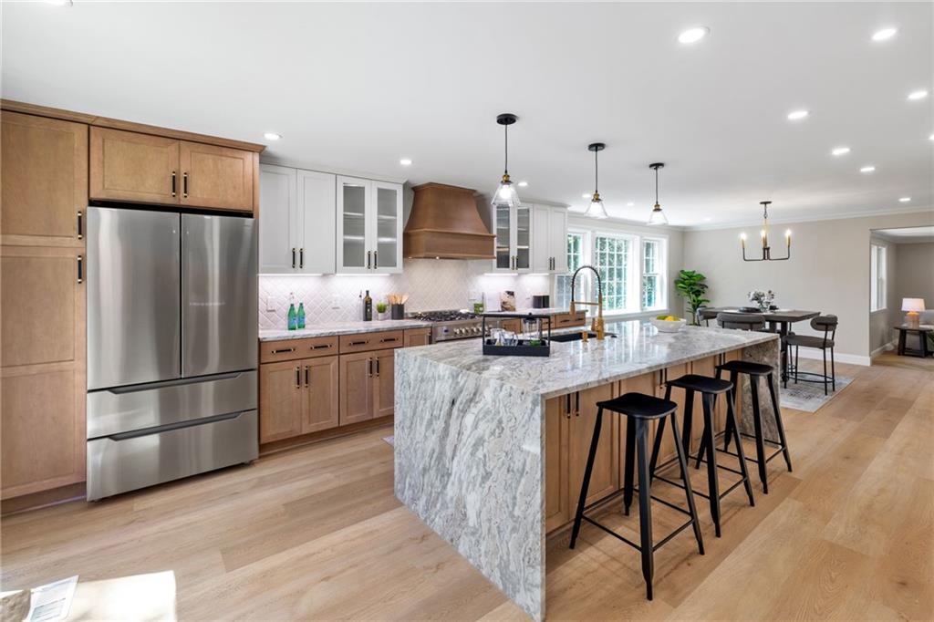 8241 Thompson Run Road Pittsburgh, PA 15237 - Photo 18 of 47 a kitchen with stainless steel appliances granite countertop a refrigerator a stove a sink a dining table and chairs with wooden floor