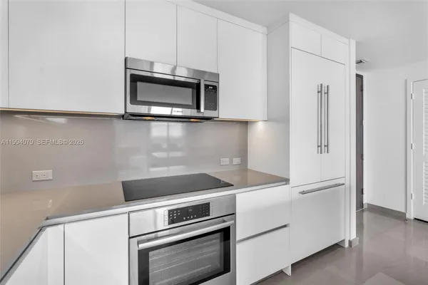 a kitchen with stainless steel appliances a stove top oven a sink a dining table and chairs with wooden floor