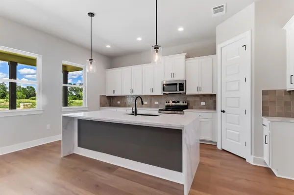 a kitchen with stainless steel appliances kitchen island a white cabinets and a wooden floor
