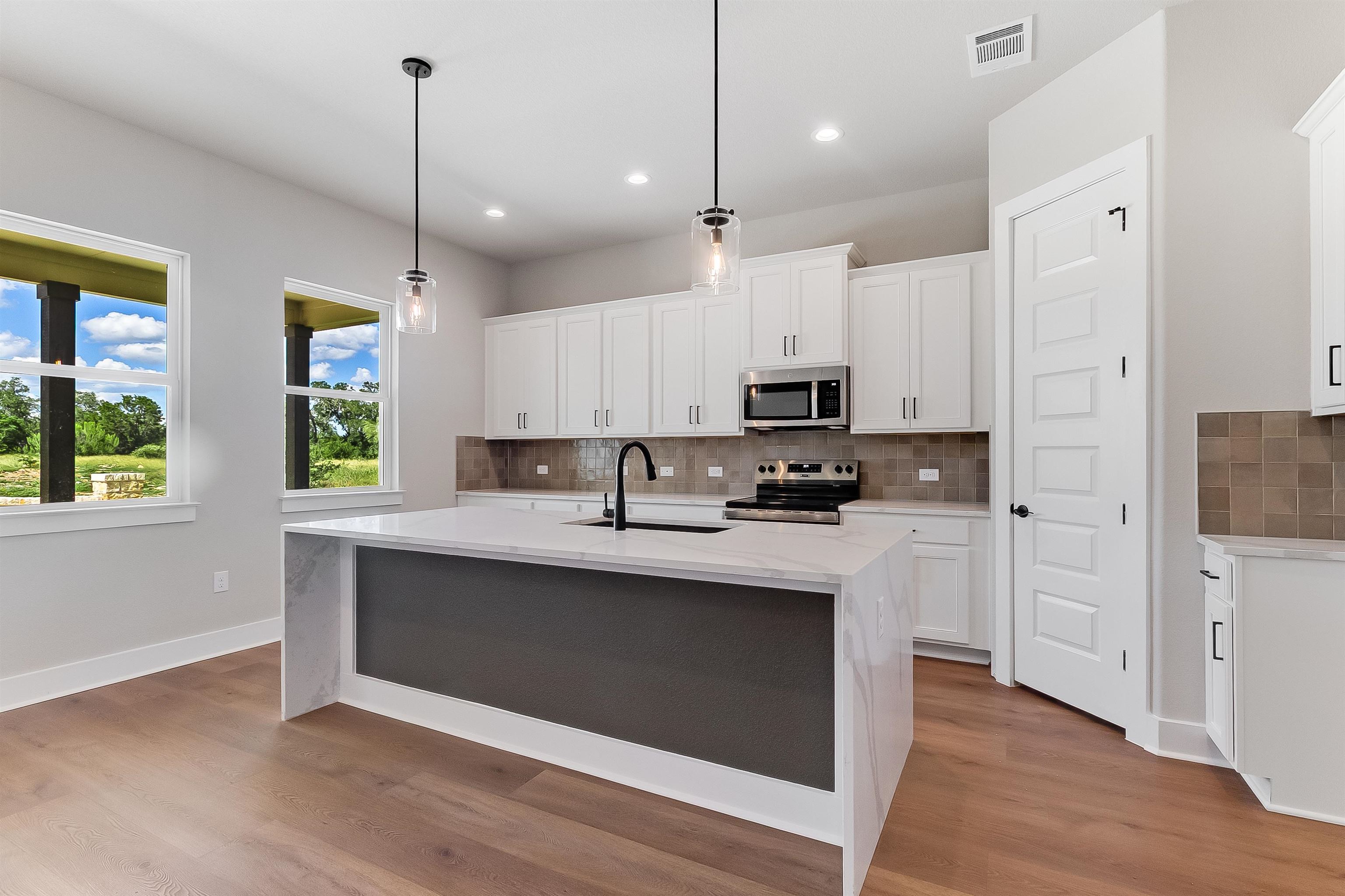 124 Draper Lane Bertram, TX 78605 - Photo 7 of 30 a kitchen with stainless steel appliances kitchen island a white cabinets and a wooden floor