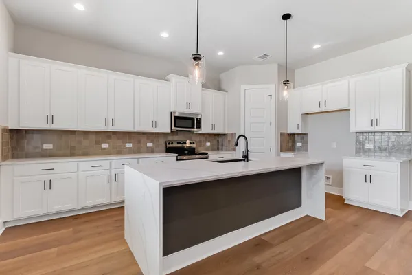 a kitchen with stainless steel appliances kitchen island granite countertop a sink a stove a refrigerator and white cabinets