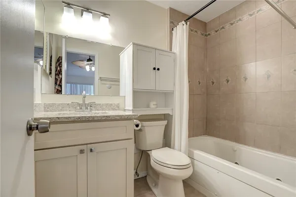 a bathroom with a granite countertop sink a toilet and shower