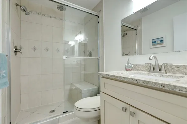 a bathroom with a granite countertop sink a toilet and shower