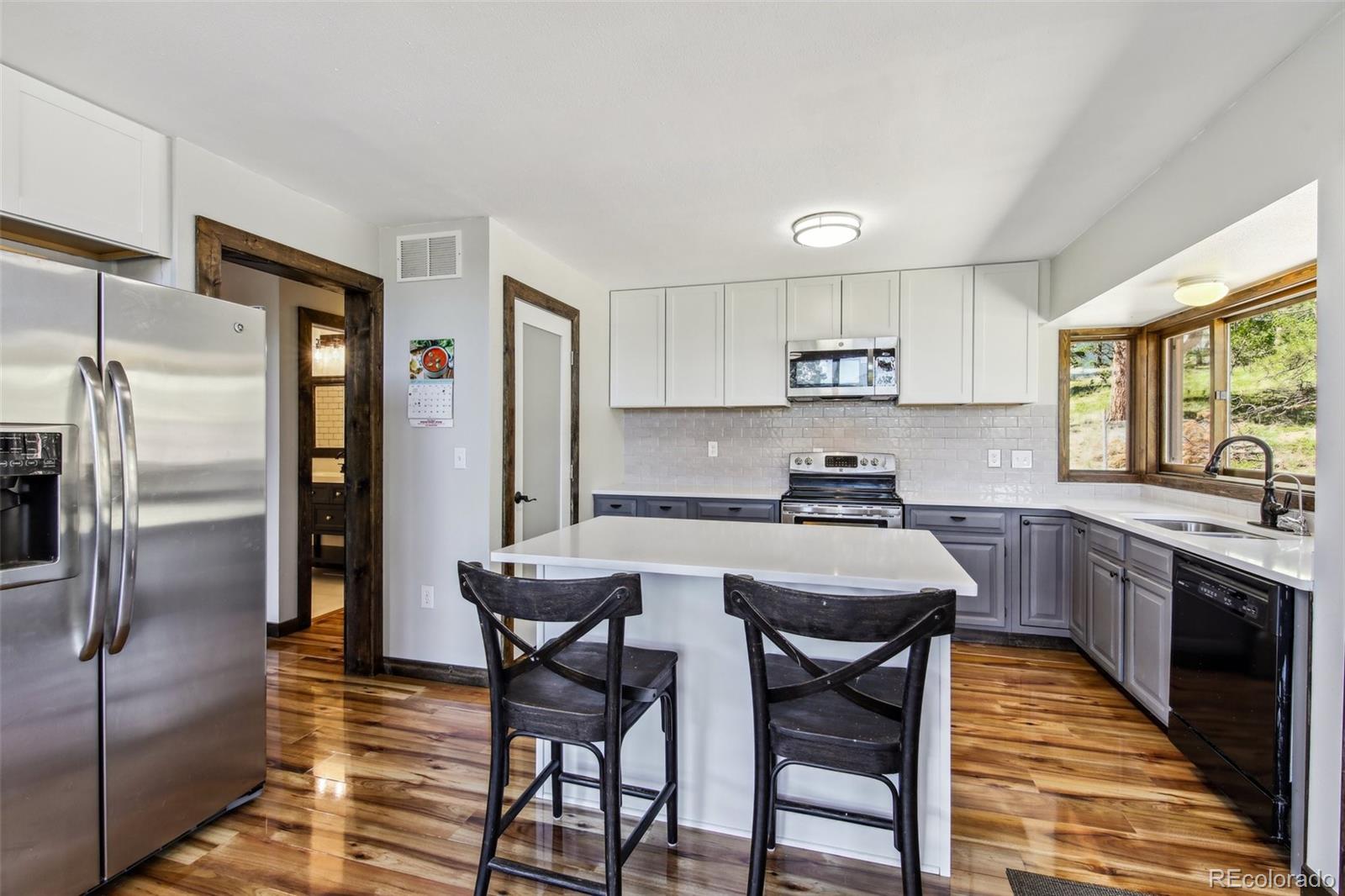 141 Tall Timber Lane Bailey, CO 80421 - Photo 15 of 40 a kitchen with stainless steel appliances granite countertop a stove a refrigerator a sink a stove and white cabinets with wooden floor