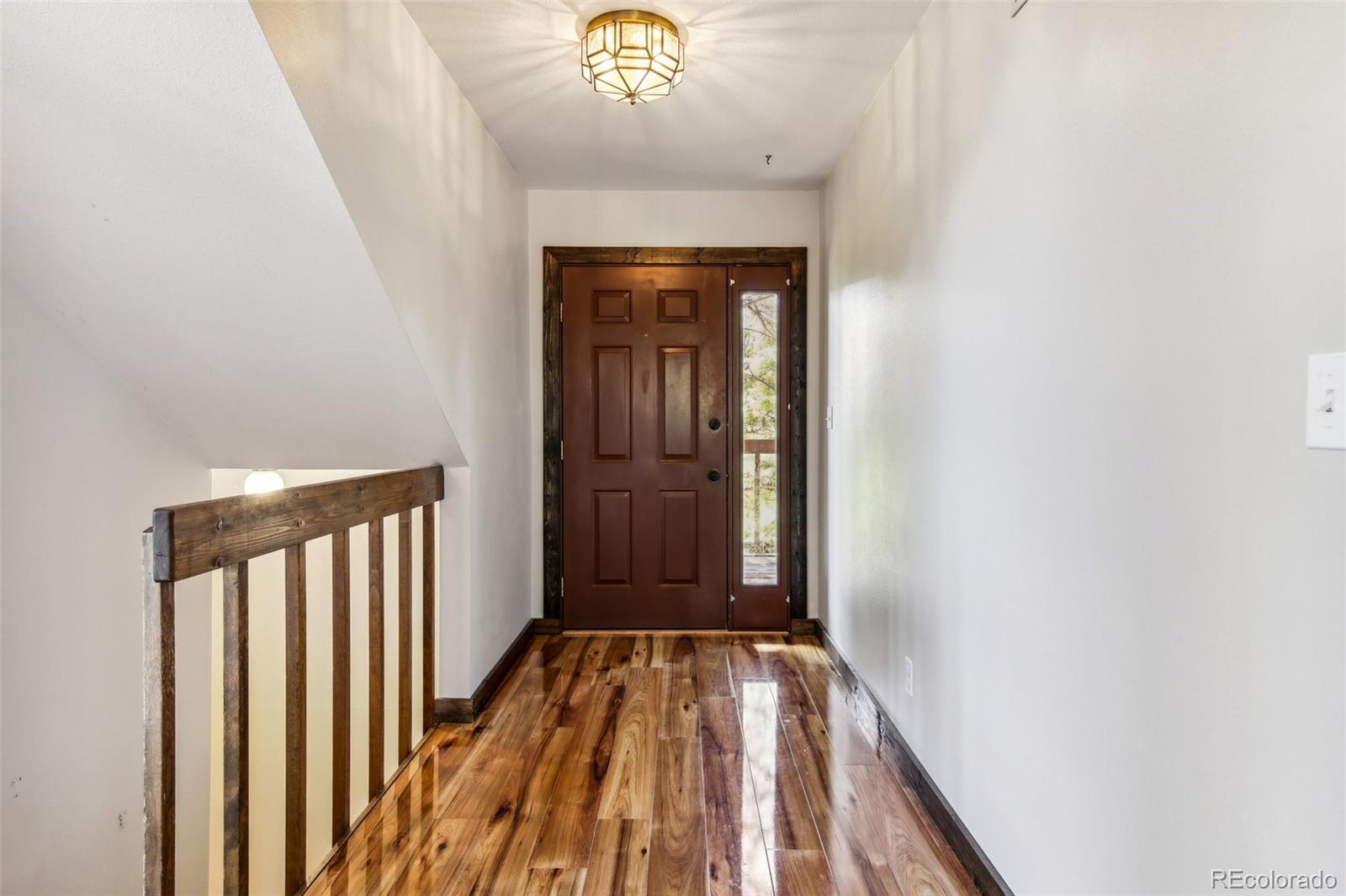 141 Tall Timber Lane Bailey, CO 80421 - Photo 31 of 40 a view of a hallway with wooden floor and a chandelier