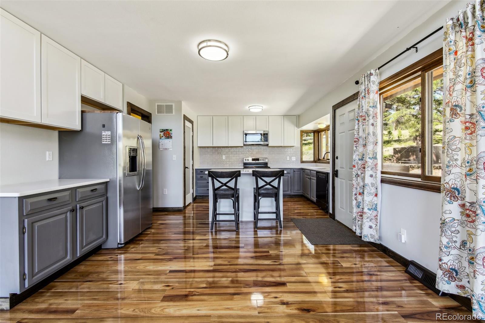 141 Tall Timber Lane Bailey, CO 80421 - Photo 10 of 40 a kitchen with stainless steel appliances kitchen island granite countertop wooden floor a dining table and chairs