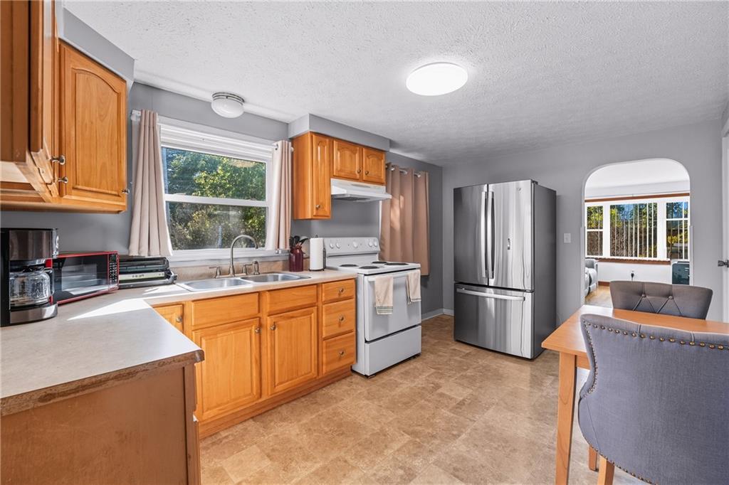105 Williamson Road Greenville, PA 16125 - Photo 9 of 27 a kitchen with stainless steel appliances granite countertop a refrigerator a stove a sink a dining table and chairs