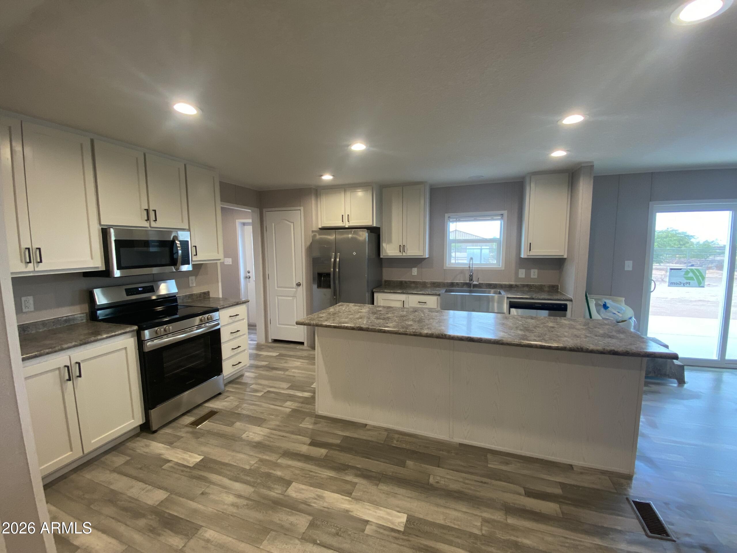 519 South Ortega Road Stanfield, AZ 85172 - Photo 15 of 29 a large kitchen with granite countertop a stove top oven a sink a counter space and cabinets