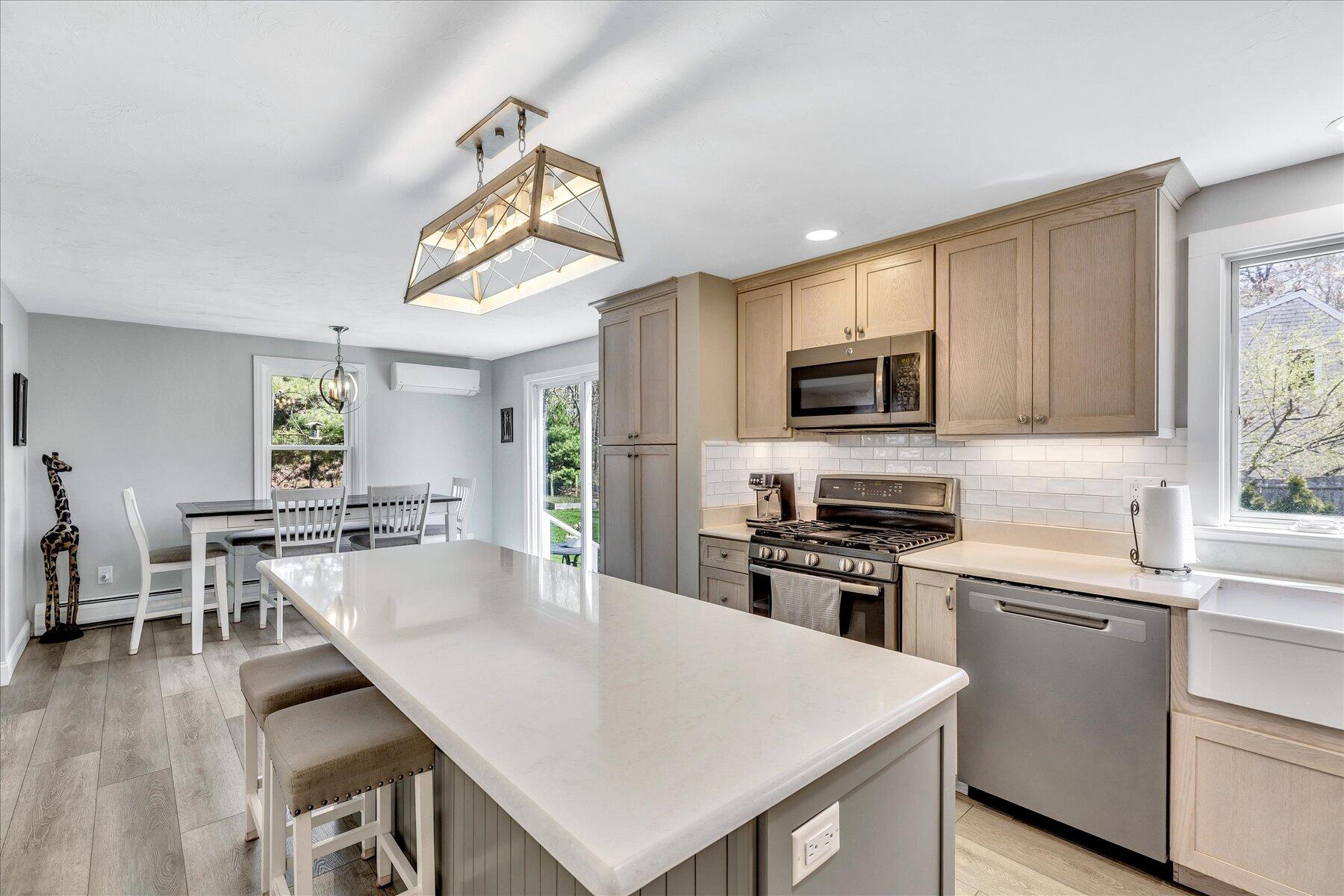 12 Drew Lane Mashpee, MA 02649 - Photo 19 of 49 a kitchen with stainless steel appliances granite countertop a stove a sink a microwave a dining table and chairs with wooden floor
