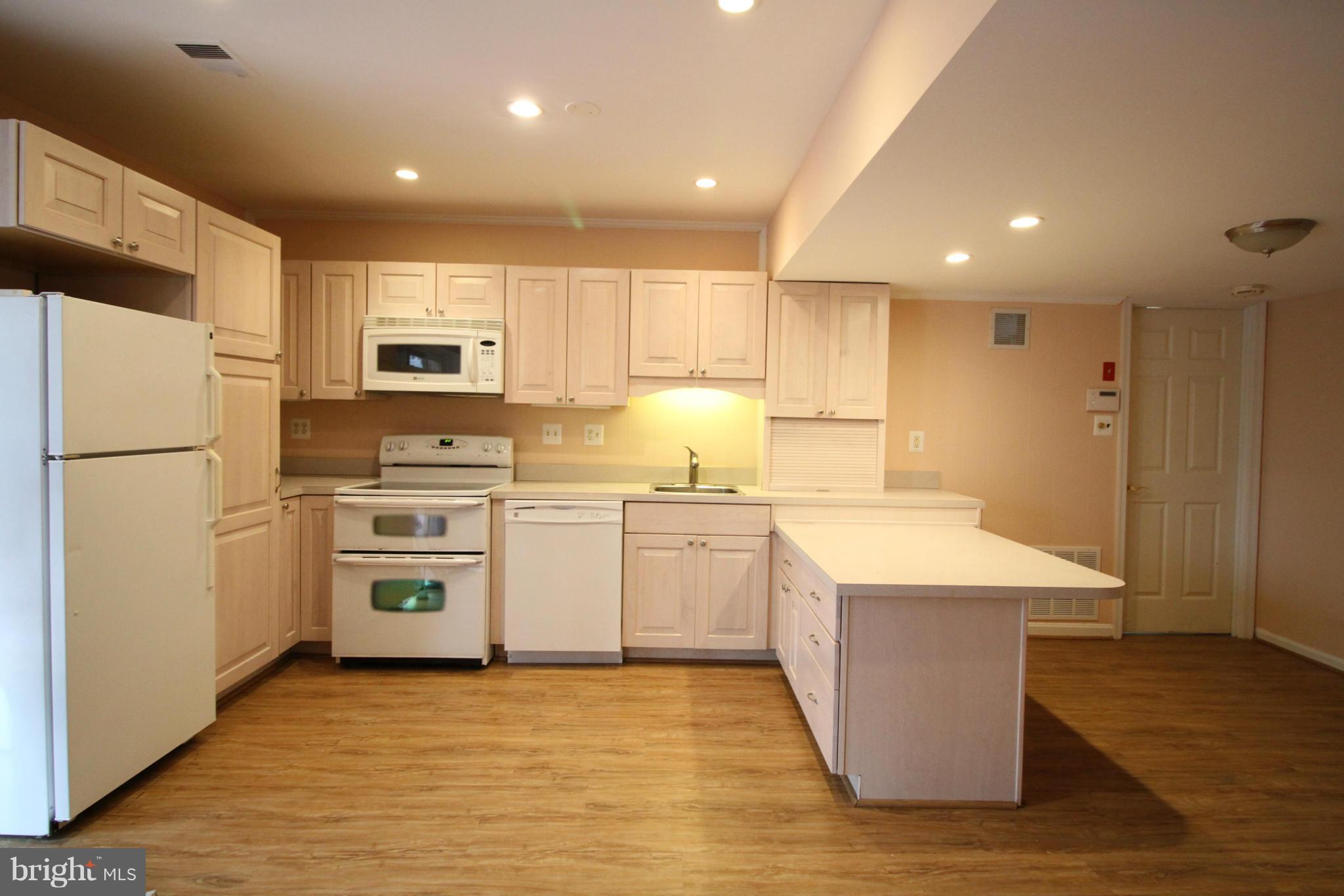 2646 Wild Cherry Place Reston, VA 20191 - Photo 22 of 26 a kitchen with granite countertop a refrigerator oven a sink dishwasher and white cabinets with wooden floor