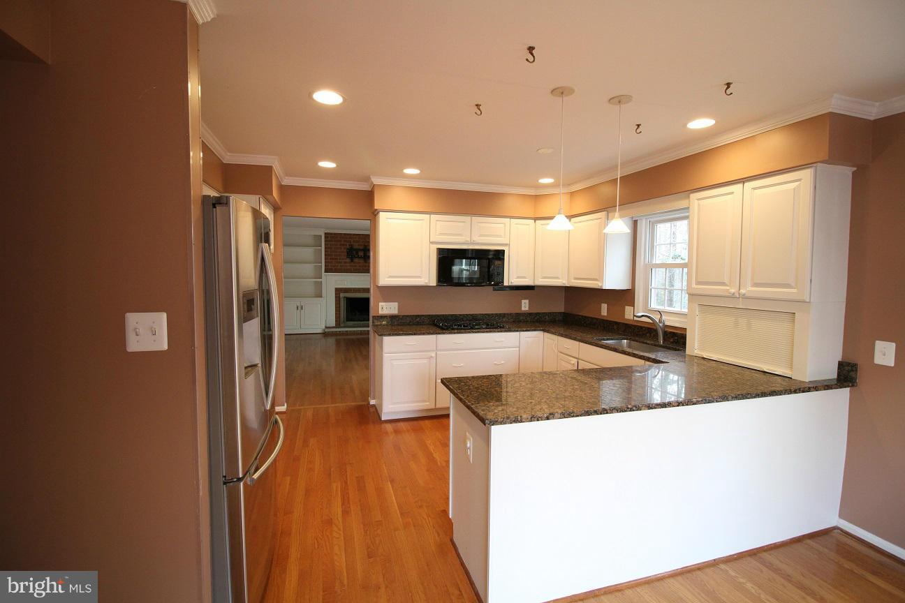 2646 Wild Cherry Place Reston, VA 20191 - Photo 7 of 26 a view of a kitchen with kitchen island a large counter top space a sink stainless steel appliances and cabinets