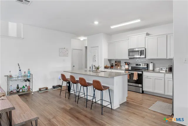 a kitchen with stainless steel appliances granite countertop a table chairs sink refrigerator and cabinets