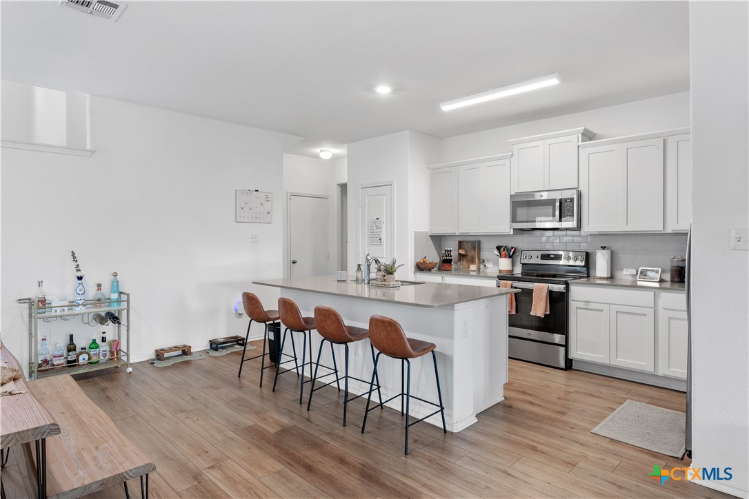129 Rowdy Yates Way Jarrell, TX 76537 - Photo 8 of 41 a kitchen with stainless steel appliances granite countertop a table chairs sink refrigerator and cabinets