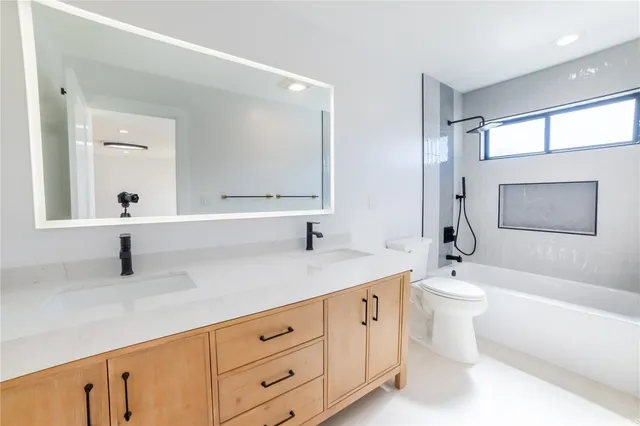 a spacious bathroom with a double vanity sink a toilet and a large mirror