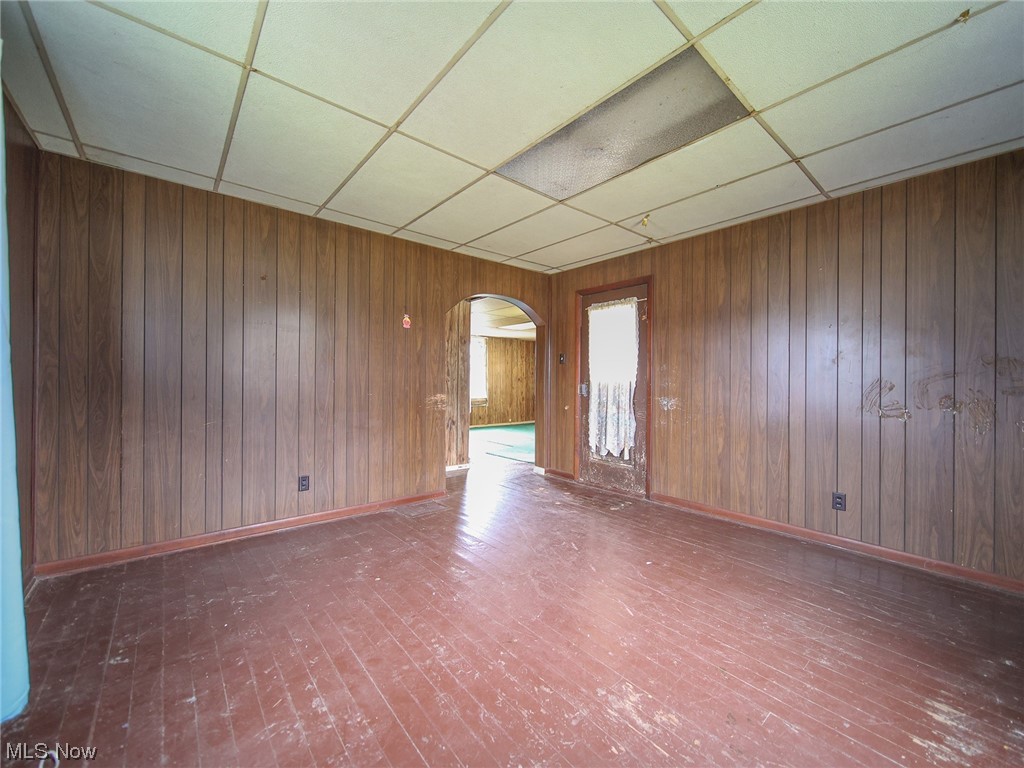 12432 Glasgow Road Southwest Port Washington, OH 43837 - Photo 13 of 31 Unfurnished room featuring a drop ceiling, dark hardwood / wood-style flooring, and wood walls