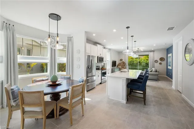 a kitchen that has a lot of white cabinets and stainless steel appliances