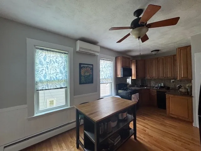 a kitchen with stainless steel appliances granite countertop a stove a refrigerator a sink a dining table and chairs with wooden floor