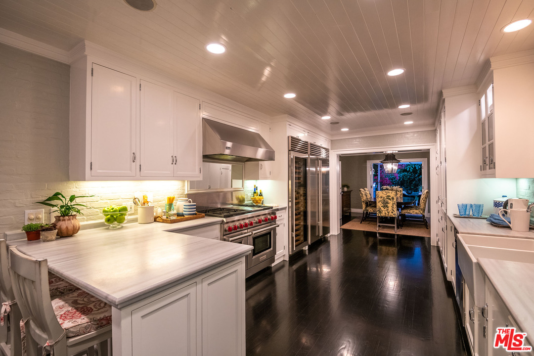 120 Homewood Road Los Angeles, CA 90049 - Photo 14 of 47 a kitchen with a sink a stove and chairs with wooden floor