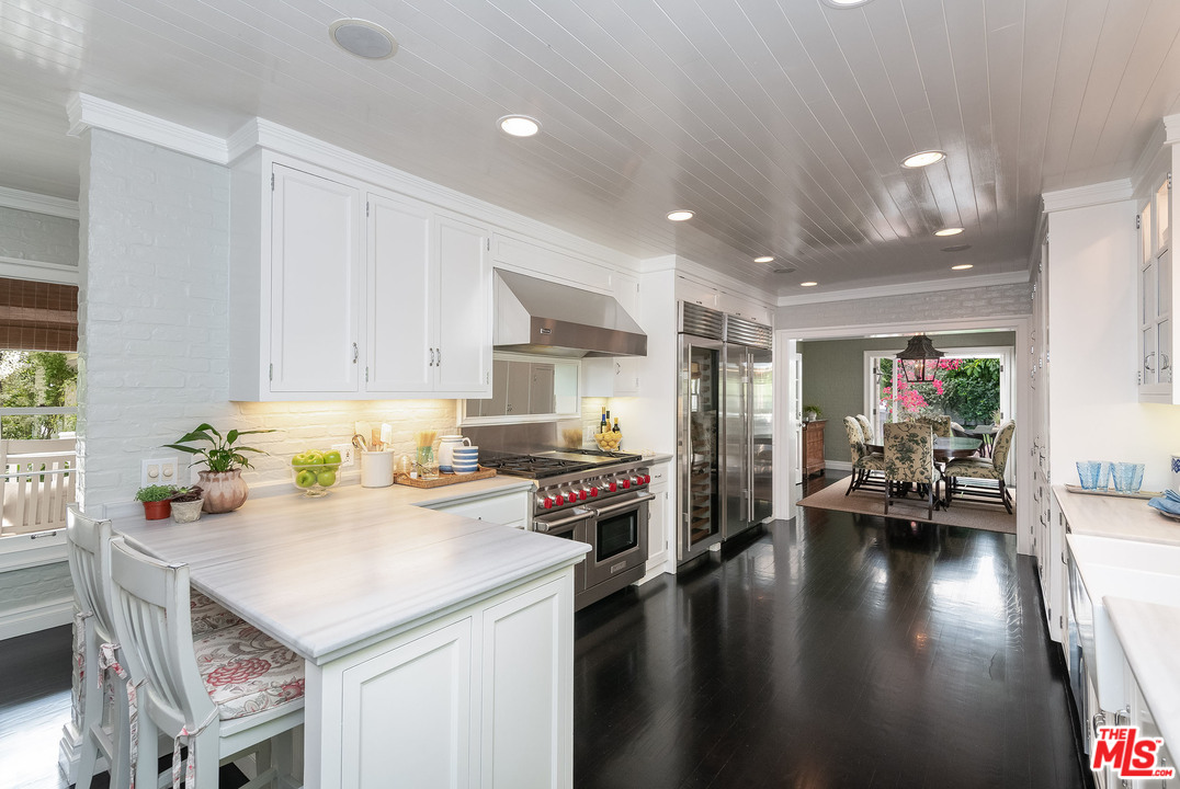 120 Homewood Road Los Angeles, CA 90049 - Photo 35 of 47 a kitchen with a sink a stove and chairs with wooden floor