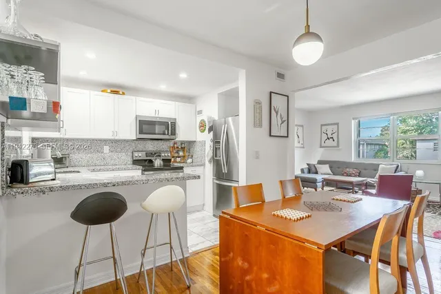 a open kitchen with stainless steel appliances granite countertop a stove a refrigerator a kitchen island a table and chairs in it