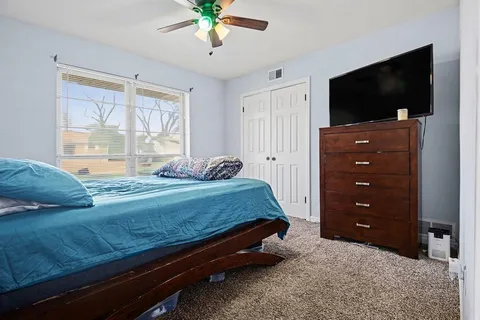 a bedroom with a bed flat screen tv and a chandelier