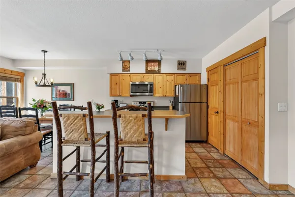 a dinning room with stainless steel appliances kitchen island granite countertop a table chairs and a refrigerator