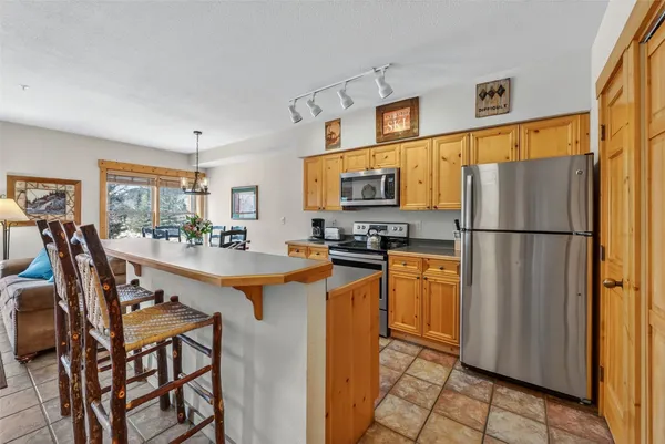 a kitchen with stainless steel appliances granite countertop a refrigerator a stove a sink dishwasher and a refrigerator with wooden floor